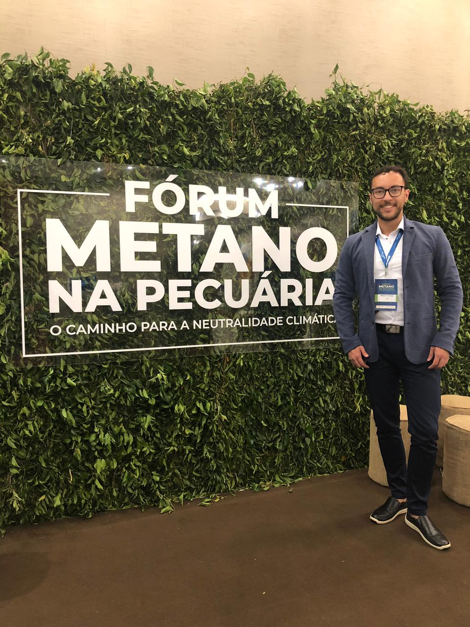 Retrato de Anselmo Penha em frente a letreiro do evento Fórum Metano na Pecuária